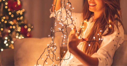 woman happily untangling Christmas lights