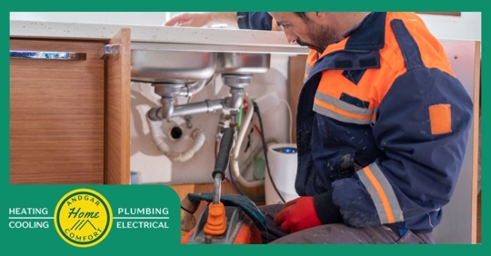 Plumber inspecting kitchen sink drain plumbing