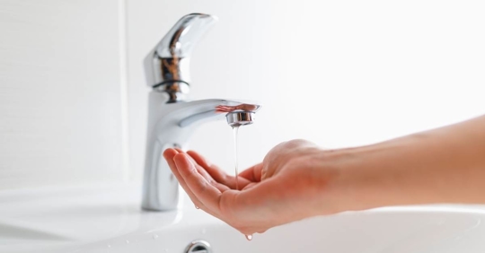 hand under faucet with low pressure water stream